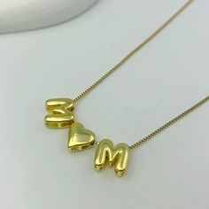 Bring joy and whimsy to your jewelry collection with our Custom Bubble Balloon Letters Necklace. This playful necklace features a delicate gold chain adorned with fun, bubble balloon-shaped letters and special characters like a heart. Perfect for customizing with a name, meaningful word, date, or initials, this necklace adds a touch of lighthearted charm to any outfit. Trendy Personalized Yellow Gold Name Necklace, Trendy Necklaces For Birthday And Mother's Day, Gold Initials Name Necklace For Mom, Gold Initials Name Necklace As Gift For Mom, Gold Initial Necklace With Adjustable Chain For Mother's Day, Gold Charm Necklace Custom Name For Mom, Gold Charm Necklace With Custom Name For Mom, Gold Initial Necklace For Mother's Day, Trendy Initial Necklace For Mother's Day Gift