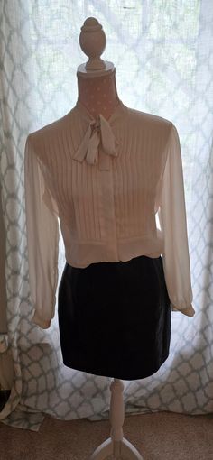 Lovely Necktie Sheer Cream Blouse from Saks Fifth Avenue Size 10 This is such a great Victorian style vintage blouse.  It is sheer and has pleating on the front. There is a concealed button band that makes this blouse even more elegant. This blouse is from the 1980's.   100 % Polyester.   I paired it with a great leather skirt that is also listed in my shop.  *Skirt is not included Comes from a smoke free and pet free home. Vintage Cream Party Blouse, Luxury Sheer Collared Blouse, Vintage Cream Blouse With Ruffled Collar, Vintage Blouse With Ruffled Collar And Button Closure, 1960s Blouse, Shop Skirt, Cream Blouse, Vintage Blouse, Womens Blouses