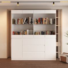 a white bookcase with books on it in a living room next to a potted plant