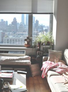 a living room filled with furniture and a large window overlooking the cityscape in the distance