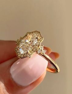 a woman's hand holding a yellow gold ring with two diamonds on the side