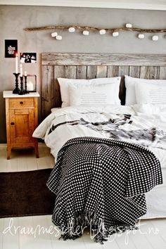 a bed with white sheets and black and white blankets on top of it next to a night stand