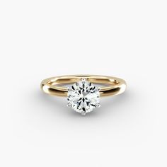 a yellow gold engagement ring with a round brilliant cut diamond in the center, on a white background