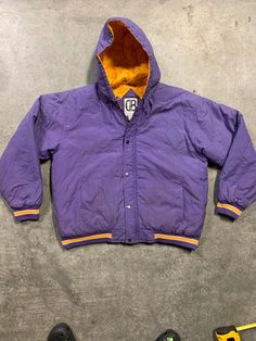 "90s 80s Hoodie Puffer Jacket.  This jacket has that Starter Jacket sporty vibe you would see in an old school Bell Biv Devo video.  It can also pass for a Lakers jacket. Stay warm and cool 😎 in this lovely 90s puffer.  It is a great jacket for your winter escapades.  Have fun in this puffy. The vintage item you are viewing is charmingly aged with time, therefore, minor wear should be expected and embraced.  The jacket has very light and minor blemishes and is in good vintage condition. Measure Casual Puffer Windbreaker For Streetwear, Hooded Outerwear For Streetwear During Sports Season, Streetwear Hooded Jacket With Fleece Lining, Purple Streetwear Outerwear With Drawstring Hood, Purple Outerwear With Drawstring Hood For Streetwear, Purple Drawstring Hood Outerwear For Streetwear, Winter Sports Hooded Varsity Jacket, Casual Purple Varsity Jacket For Winter, Winter College Outerwear In Purple