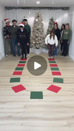 a group of people standing in front of a christmas tree with red and green stripes on the floor