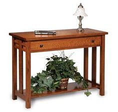 a wooden table topped with a potted plant and a lamp on top of it