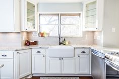 a clean kitchen with white cabinets and stainless steel dishwasher in the corner,