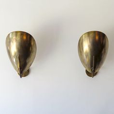 two brass wall mounted sconces on a white wall