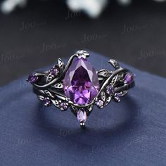 an amethorate ring with purple stones and leaves on it, sitting on top of a blue cloth