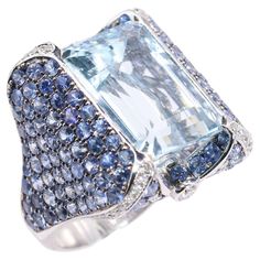 S.Georgios designer presents a magnificent 18 Karat White Gold Ring featuring a 15.70 Carats emerald-cut Aquamarine at the center, surrounded by an array of Sapphires total weight of 8.16 Carats on the band and White Diamonds total weight of 0.80 Carats in the corners. This statement ring is a true masterpiece, blending the serene beauty of aquamarine with the luxurious sparkle of sapphires and white diamonds. Handmade in our Athens, Greece workshop, this exquisite piece is perfect for those seeking a unique and elegant addition to their jewelry collection. Size: 7 (can be custom-adjusted to the desired size) Front Width: 24 mm Back Width: 6 mm All Georgios Collections jewelry is handmade in our workshop in Greece and is of exquisite quality. For regular updates please visit our storefront The Collective, Sapphire Diamond Ring, Athens Greece, Sapphire Diamond, White Diamonds, Cocktail Rings, White Gold Rings, Solitaire Ring, Emerald Cut