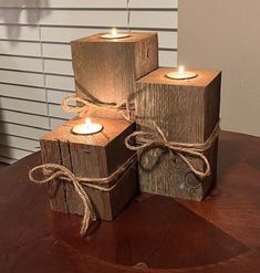 three wooden blocks with lit candles tied to them