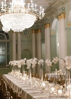 a long table is set up with white flowers and candles for a formal dinner or reception