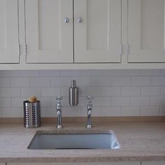 a kitchen with white cabinets and marble counter tops, including a stainless steel farmhouse sink