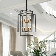 a chandelier hanging from the ceiling in a living room with stairs and windows