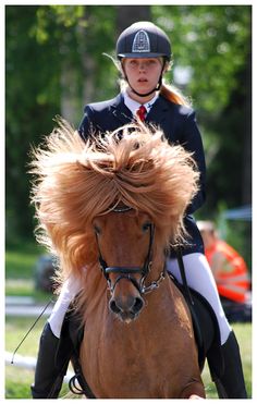 a woman riding on the back of a brown horse with long hair in it's mane