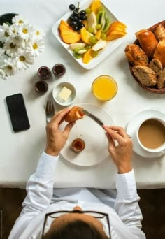 a person sitting at a table with food and drinks in front of them on plates