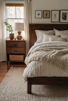 a bed sitting in a bedroom next to a window covered in white blankets and pillows