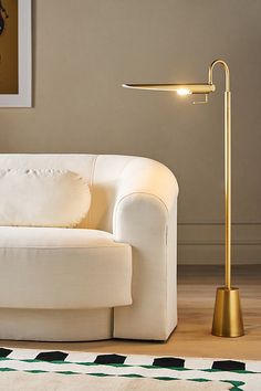 a white couch sitting next to a lamp on top of a hard wood floor in a living room