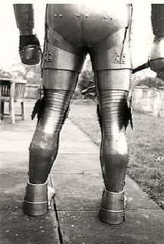 the legs and butts of a man in large metal pants are seen from behind