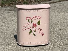 a pink trash can with flowers painted on it