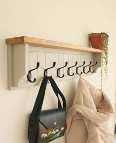 a coat rack and purse hanging on a wall next to a potted plant in a room