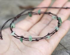 a hand is holding a bracelet with green beads