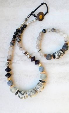 "Mixed media . Earthy elegance . Great texture . Beach inspired . Coastal calm . A little rustic . Worldly . Alluring . Recycled glass . Reuse . Repurpose . Statement making . One-of-a-kind . Quality gemstones . Wood . Nut & bone beads . Ethiopian metals . Handmade . Imaginative .  Necklace is 20\" to 23\" in length. 14mm to 30mm African recycled glass beads, 6mm pearls, 8mm matte Black Agate, 12mm Quartz and electroplated Lava beads, large 16mm shell disks, fused glass disks, and shell beads. B Large Wood Bead Necklace, Coastal Calm, Earthy Elegance, Touch Of Gray, Beaded Jewelry Necklaces, Recycled Glass Bead, Wood Bead Necklace, Lava Beads, Bone Beads