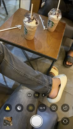 a person sitting at a table with two cups of ice cream on top of it