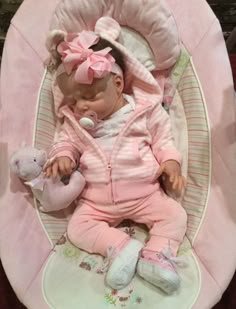 a baby in a pink outfit laying down with a stuffed animal