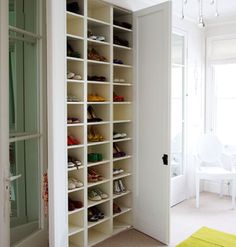 a white closet filled with lots of shoes next to a door and window sill