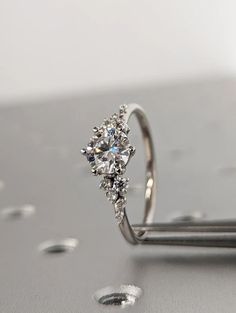 a diamond ring sitting on top of a metal surface with drops of water around it