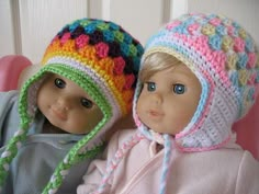 two dolls wearing knitted hats sitting next to each other