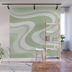 a green and white swirl wall mural in a living room with wooden floors, bookshelves