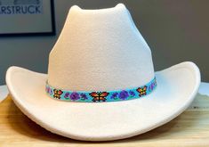 The size for this hatband is 21 1/2 inches x 1 inch with 10 inch black colored leather ties.  Butterflies and Flowers Hatband!  This beautiful one features monarch butterflies and purple flowers with a turquoise color background.  This beautiful beaded loomed hatband for cowboy hats is constructed from an original pattern designed by Mary's Hatbands and is made from Miyuki delica glass seed beads. It's been woven and reinforced with extremely strong Nymo nylon thread specifically designed for be Beaded Hat Band Patterns, Beaded Hat Bands, Beaded Hat, Chapeau Cowboy, Monarch Butterflies, Butterflies And Flowers, Cow Boy, Color Background, Flowers Pattern