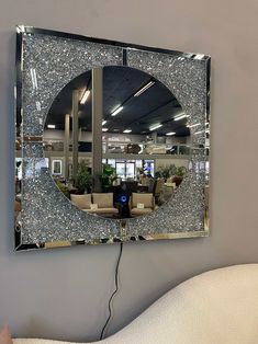 a mirror that is hanging on the wall above a chair and couch in front of it