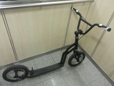 an electric scooter sitting on the floor next to a metal hand rail in a public bathroom