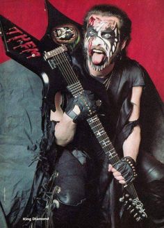 a man with his face painted like a demon holding an electric guitar in front of him