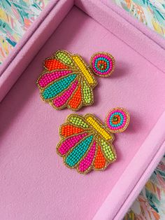 two colorful butterfly pins sitting on top of a pink box