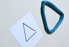 a piece of paper with a blue object on it next to a cut out triangle