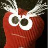 a red knitted hat with white feathers on it's head and eyes that look like an angry bird