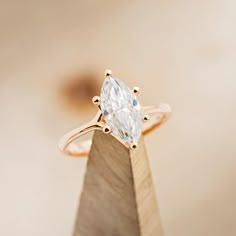 a pear shaped diamond sits on top of a wooden stand in front of a beige background