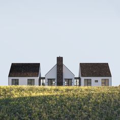 two white houses sitting on top of a lush green field