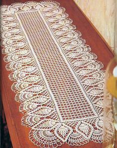 an old lace table runner is on the floor next to a vase with yellow flowers