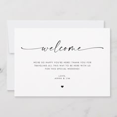 a white card with the words welcome written in cursive writing on it and a black heart