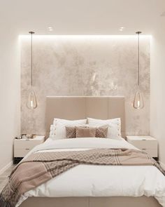 a large bed sitting under two lamps in a bedroom next to a wall mounted light