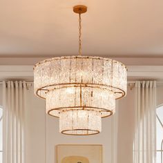 a chandelier hanging from the ceiling in a room with white walls and curtains