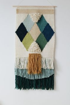 a woven wall hanging with tassels and fringes on it's sides