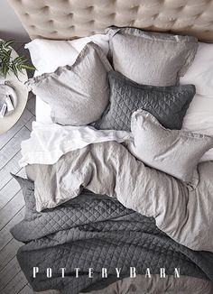 an overhead view of a bed with grey and white linens, pillows and blankets