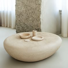 a table with two bowls on it in front of a stone wall and window sill