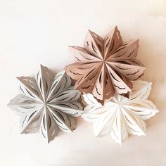 three paper snowflakes sitting on top of a white table next to each other